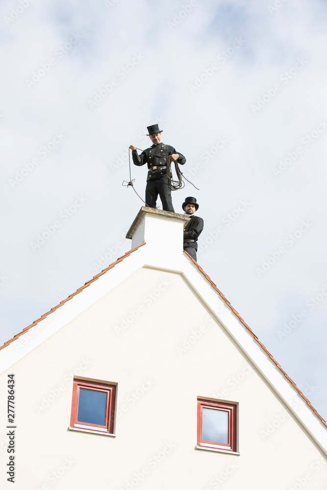 Two chimney sweeps working on house roof Two chimney sweeps working on house roof