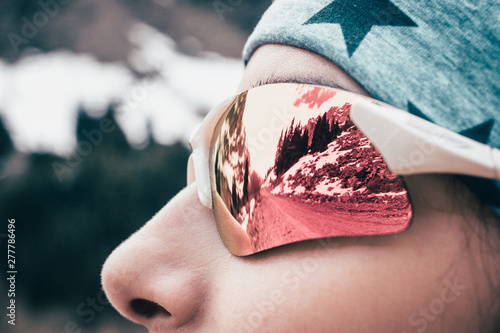 Fototapeta Naklejka Na Ścianę i Meble -  Female model close up face sunglass reflection in winter mountain.