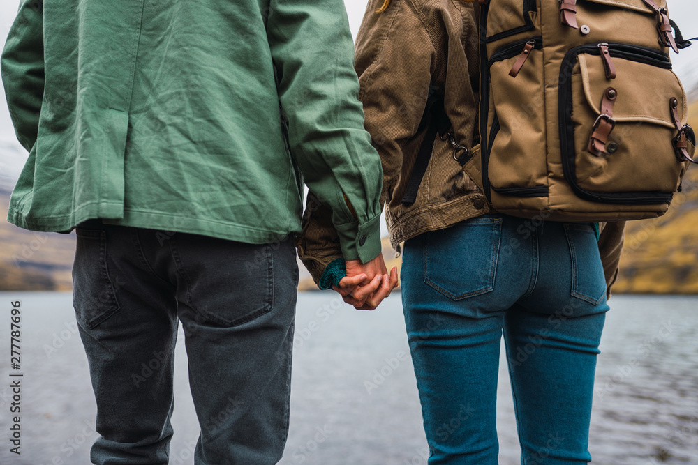back view of a couple holding hands in front a lake in Faroe Island back view of a couple holding hands in front a lake in Faroe Island