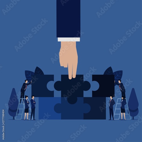 Business hand hold piece of puzzle team unite to match puzzle metaphor of cooperation and teamwork.