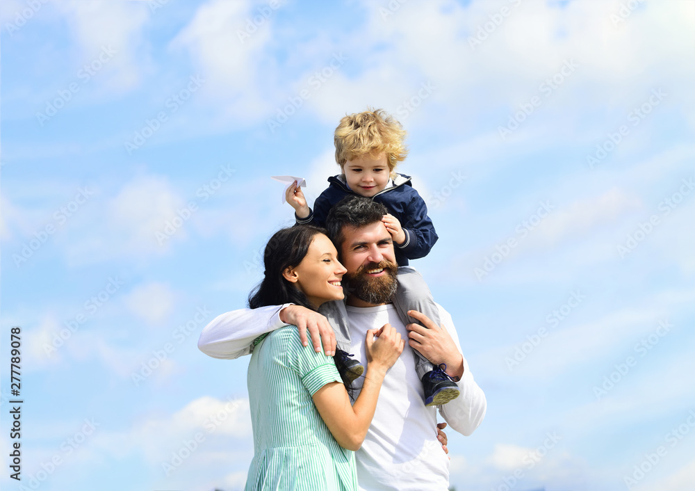 Happy family - mother, father and son on sky background in summer. Child sits on the shoulders of his father. Imagination. Happy family - mother, father and son on sky background in summer. Child sits on the shoulders of his father. Imagination.