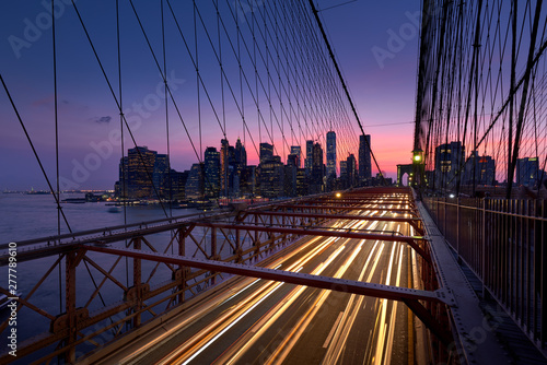 Brooklyn Bridge with light trails and view on Lower Manhattan just after Sunset. Evening in New York City  NY  USA
