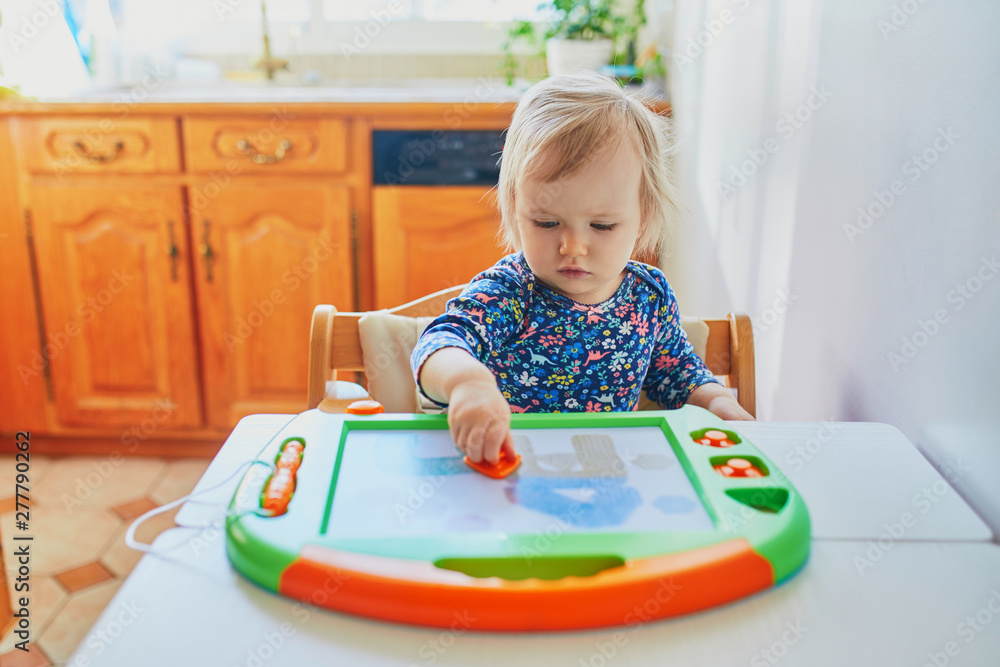 Adorable little girl drawing on magnetic magic screen Adorable little girl drawing on magnetic magic screen