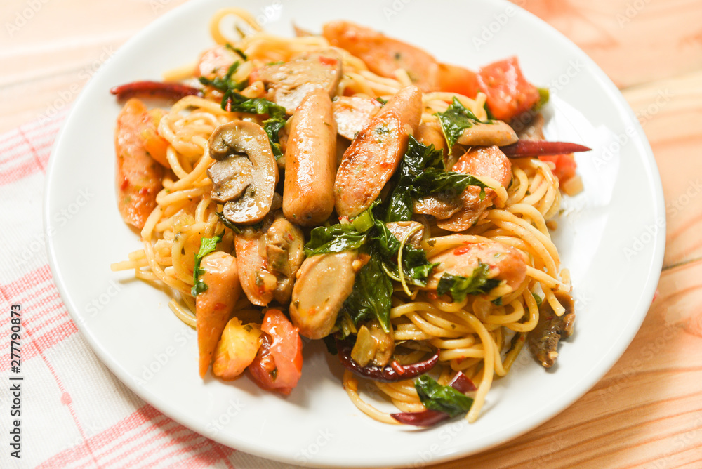 Hot and spicy Spaghetti Pasta tomato chilli and basil leaves top view - Traditional delicious Italian food spaghetti sausage on plate on the dining table