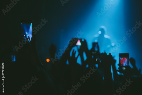 Raised up hands with cellphones recording videos from music show