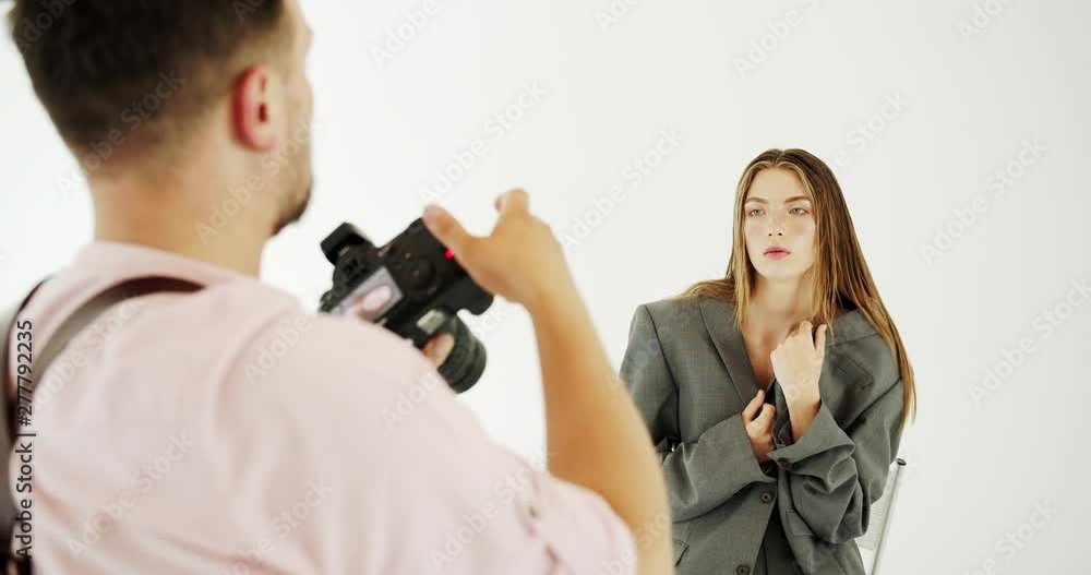 Back view of photographer taking pictures of stylish fashionable young woman dressed in oversized suit Back view of photographer taking pictures of stylish fashionable young woman dressed in oversized suit