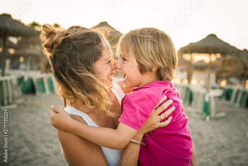 Smiling mother and son rubbing noses while standing on beach photo