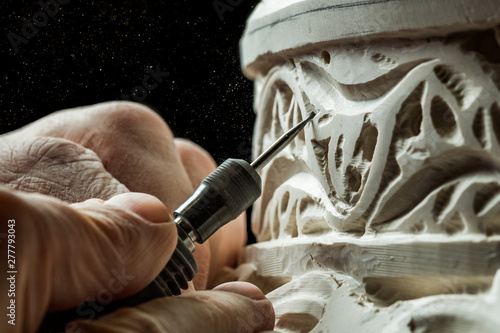 Crop hands carving ornament on plaster