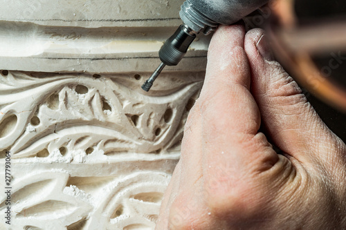Crop hands carving ornament on plaster