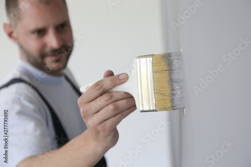 Man painting with a paintbrush over a grey wall photo