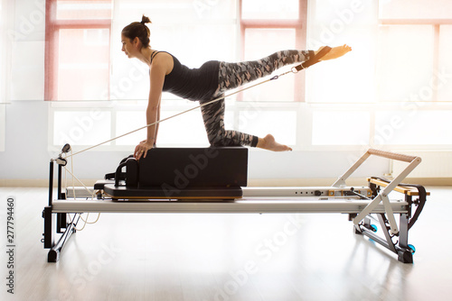 Pilates reformer workout exercises woman at gym indoor photo