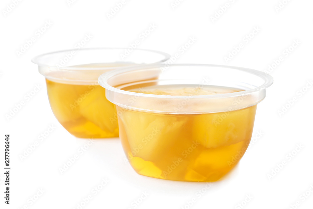 Tasty jelly desserts with slices of fruit in plastic cups on white background