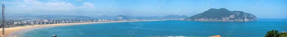 Panoramic view of Salve de Laredo Beach, Cantabria, Spain, composed of ten photographs. The rock of Santona, Cantabrian Sea and a blue sky with clouds in the background