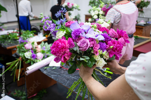 Female florist create a bouquet at workplace. Floristics workshop. Making beautiful flower bouquets and floral decorations..