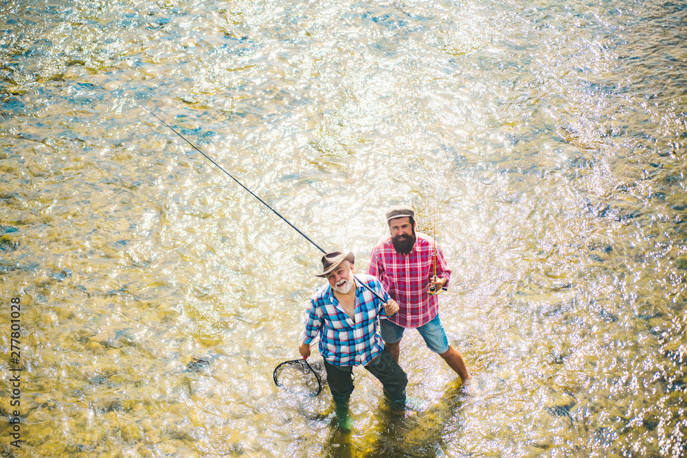 Father and boy fishing together. Brown trout fish. Fly angler on the river. Father and son relaxing together. Father and boy fishing together. Brown trout fish. Fly angler on the river. Father and son relaxing together.