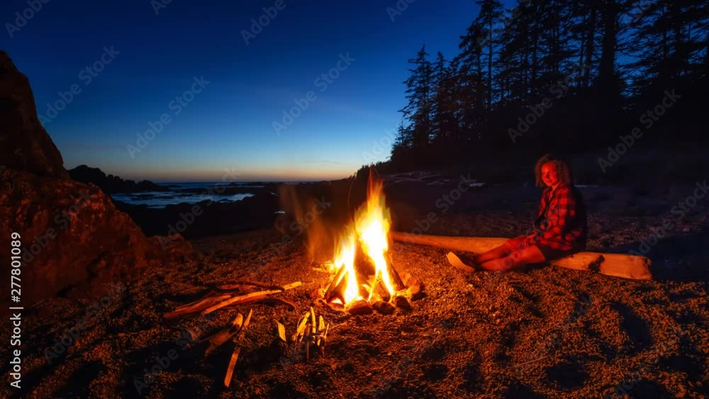 Girl enjoying a camp fire on the beach during a vibrant summer sunset. Taken in Northern Vancouver Island Ocean Coast, BC, Canada. Still Image Continuous Animation Girl enjoying a camp fire on the beach during a vibrant summer sunset. Taken in Northern Vancouver Island Ocean Coast, BC, Canada. Still Image Continuous Animation