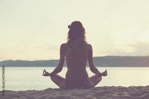 Young woman practicing yoga on the sandy beach.