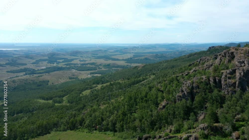 The panorama shot from the mountain. Beautiful view from the mountain. There is a cable car to the mountain. In the background is a valley with forests and lakes. The panorama shot from the mountain. Beautiful view from the mountain. There is a cable car to the mountain. In the background is a valley with forests and lakes.