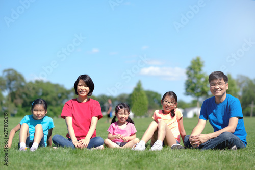 Happy Asian family with children outdoors in park during summer