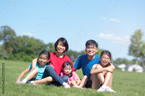 Happy Asian family with children outdoors in park during summer