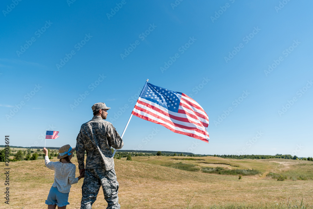 soldier holding hands with kid in straw hat and holding american flag soldier holding hands with kid in straw hat and holding american flag