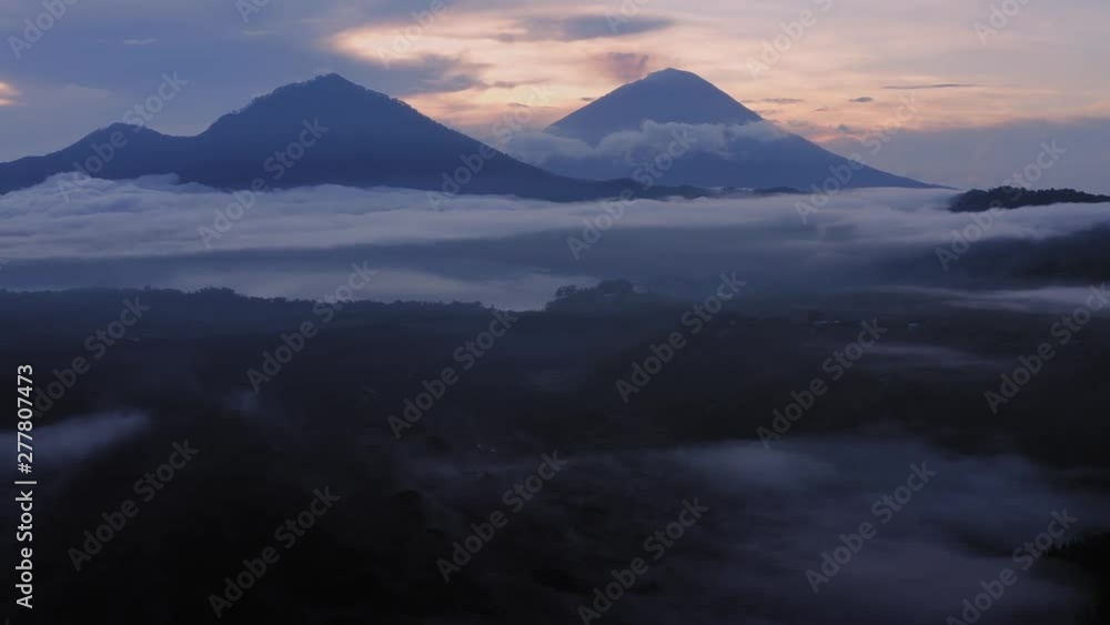 Aerial: Flying over the crater rim on a foggy morning on Mt Batur. The camera is flying towards the active volcano of Mount Agung. Bali, Indonesia Aerial: Flying over the crater rim on a foggy morning on Mt Batur. The camera is flying towards the active volcano of Mount Agung. Bali, Indonesia