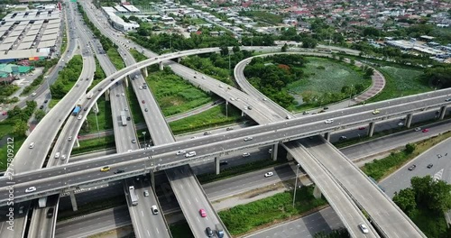 4K. Aerial view of road interchange of highway intersection with busy urban traffic speeding on the road. Junction network of transportation taken by drone.
