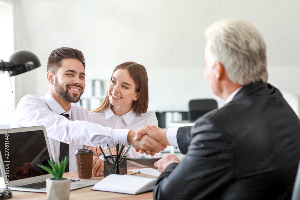 Man shaking hands with notary public in office Man shaking hands with notary public in office