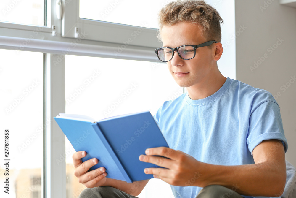 Male student reading book while preparing for exam indoors Male student reading book while preparing for exam indoors
