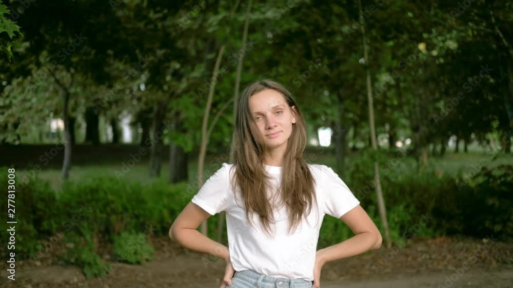 A young European brunette woman in the park is looking forward and smiling. Close up portrait A young European brunette woman in the park is looking forward and smiling. Close up portrait