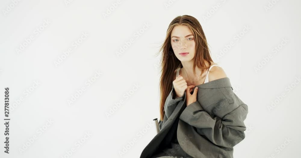 Young beautiful female model sitting on chair while posing to camera Young beautiful female model sitting on chair while posing to camera