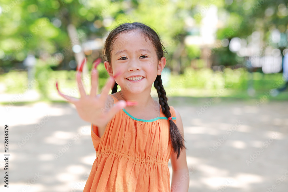 Portrait of little Asian child girl playing with Stick the flower petals to the nail like a tiger or wild animal in the garden. Focus at kid face. Portrait of little Asian child girl playing with Stick the flower petals to the nail like a tiger or wild animal in the garden. Focus at kid face.