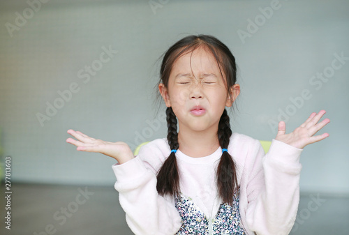 Angry little Asian child girl in classroom. Not listening. Sign and gesture concept. photo