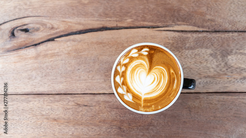 Hot art coffee cappuccino in a cup on wooden table background with copy space