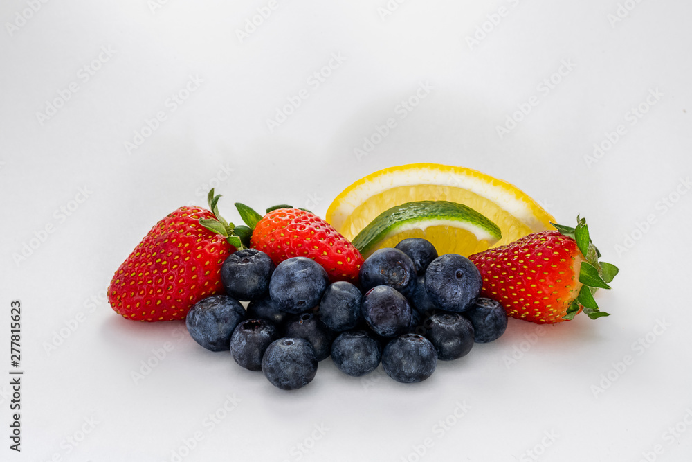 An arrangement of fresh blueberries, strawberries, lemon and lime isolated on white.