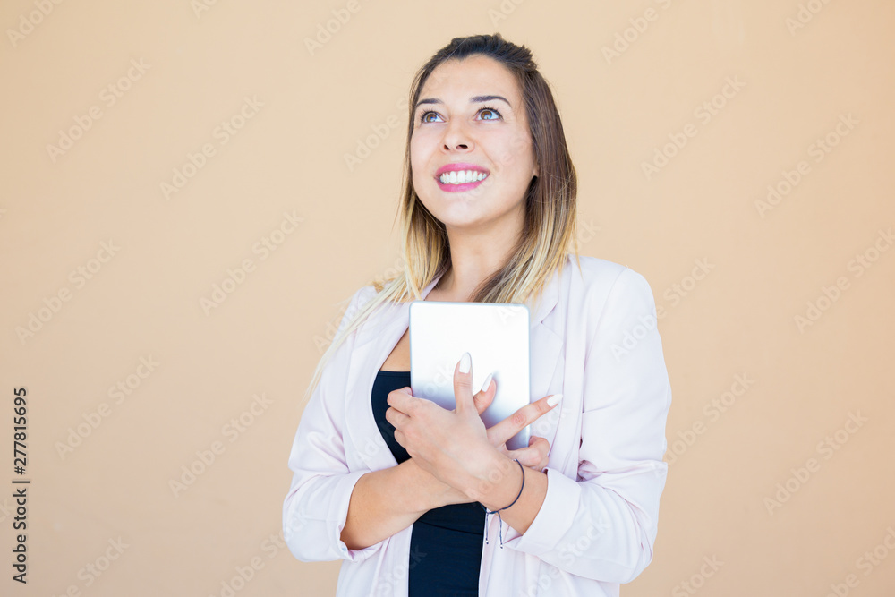Happy joyful tablet user thanking god. Young woman in white jacket embracing mobile pc, looking up and smiling. Good news or relief concept Happy joyful tablet user thanking god. Young woman in white jacket embracing mobile pc, looking up and smiling. Good news or relief concept