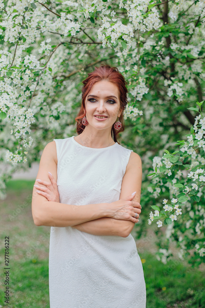 Charming woman wearing beautiful white dress under the apple tree Charming woman wearing beautiful white dress under the apple tree
