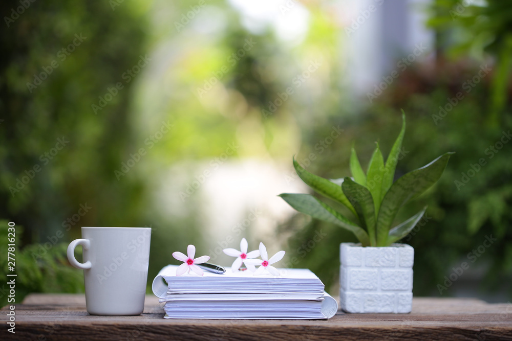 White coffee cup and notebooks on wooden table at outdoor White coffee cup and notebooks on wooden table at outdoor