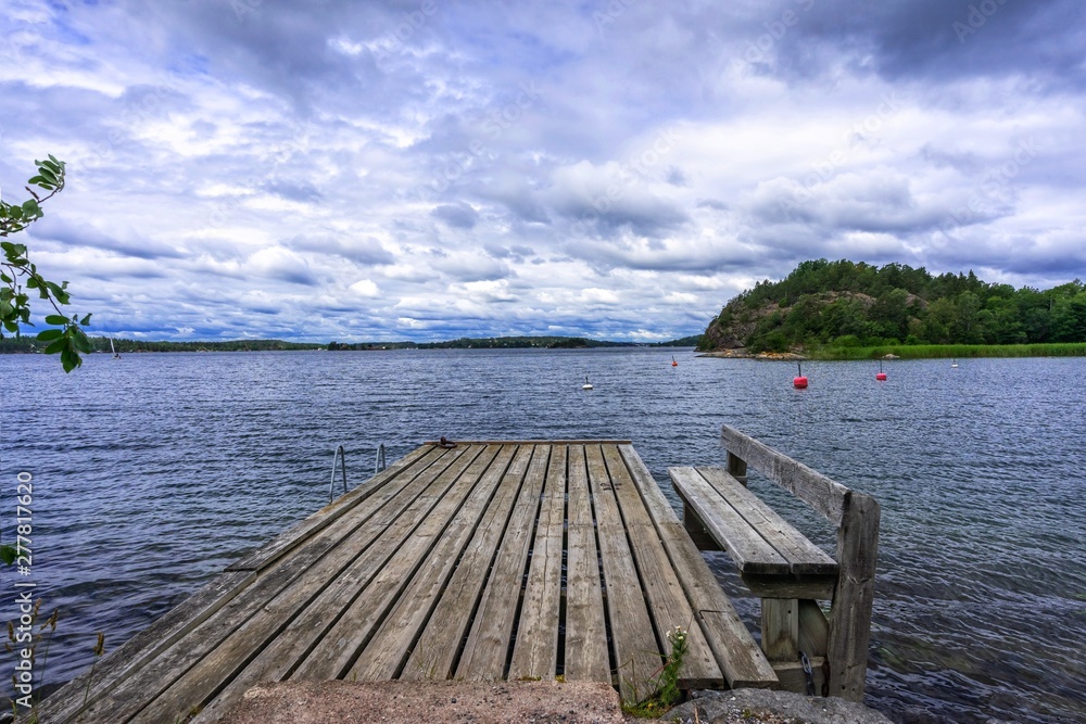 Old wooden pier. Empty berth on the Baltic sea coast. Dramatic cloudy sky. Horizon. Vintage Picture. Seascape: amazing view. Beautiful picture of sea coast line in Scandinavia. Empty jetty on cloudy d