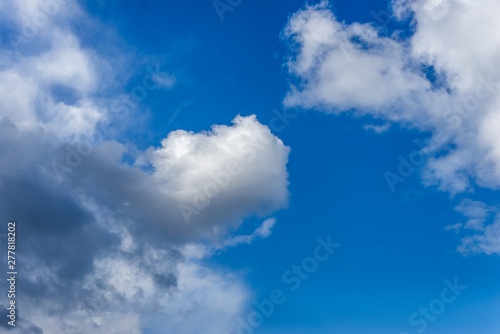 Fluffy white and grey clouds against a bright, colorful blue sky © Photography by Adri