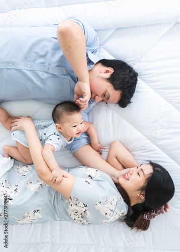 Top view of 8 months old family lay and play on bed together