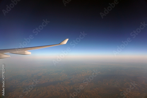 Beautiful view from the window of the aircraft. Concept and copyspase for travel, holidays and vacation. Sea, mountains, clouds, coastline, horizon, blue sky through the eyes of a traveler.