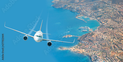 White airplane flying over above island in tropical sea - Travel Destinations Concept