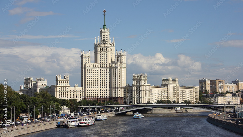 Obraz premium Russia, Moscow, Stalin skyscraper high-rise building on Kotelnicheskaya embankment, Big Ustinsky bridge and Moscow river with ships on a Sunny summer day - cityscape
