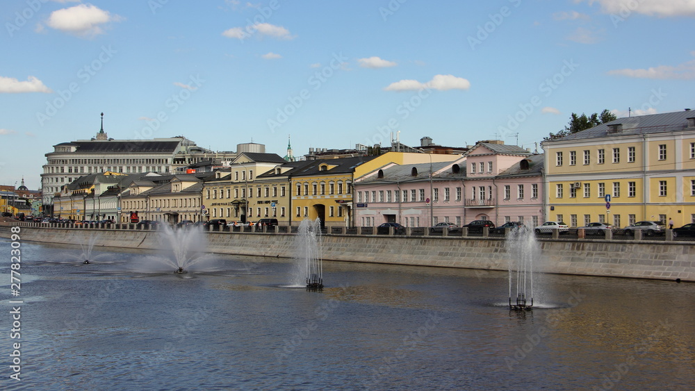 Russia, Beautiful colored old houses on Kadashevskaya embankment and water fountains on the Vodootvodny canal in Moscow on a Sunny summer day, panoramic cityscape