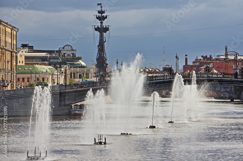 Russia, Moscow, Fountains on Vodootvodny canal, view from Bolotnaya square on background of monument to Great Peter and famous confectionery Red October on summer day against stormy sky