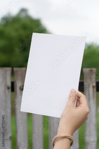 Woman holding paper blank of drawing paper paper with natural background. © blindturtle