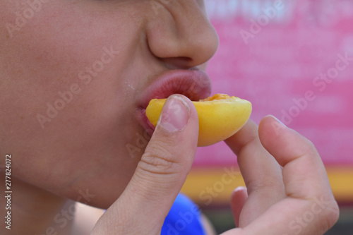Girl bites fresh fruit  close up.