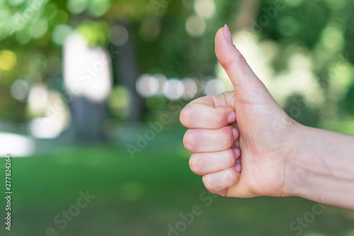 The hand of a young girl shows a sign of hitchhiking for stopping cars