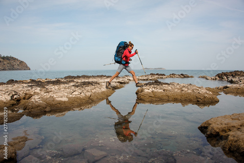 Woman with backpack treks on a sea coast photo